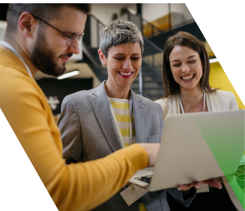 Photo of three people working at a laptop that one of them is holding