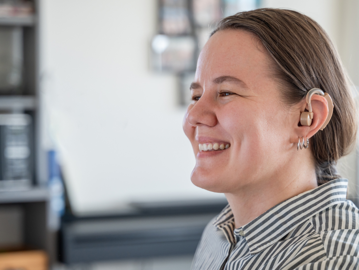 A woman smiling, wearing a hearing aid