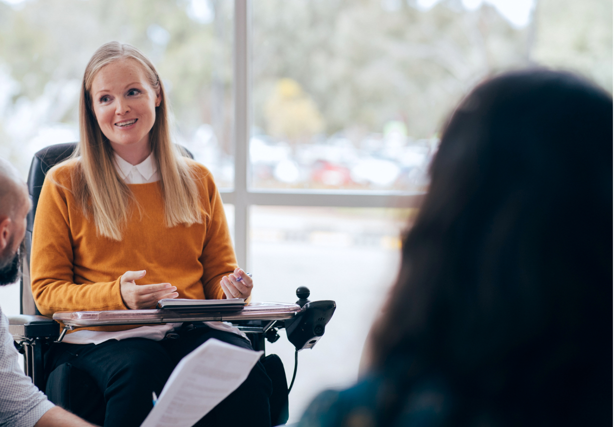 A woman using a wheelchair with a desk in a professional environment