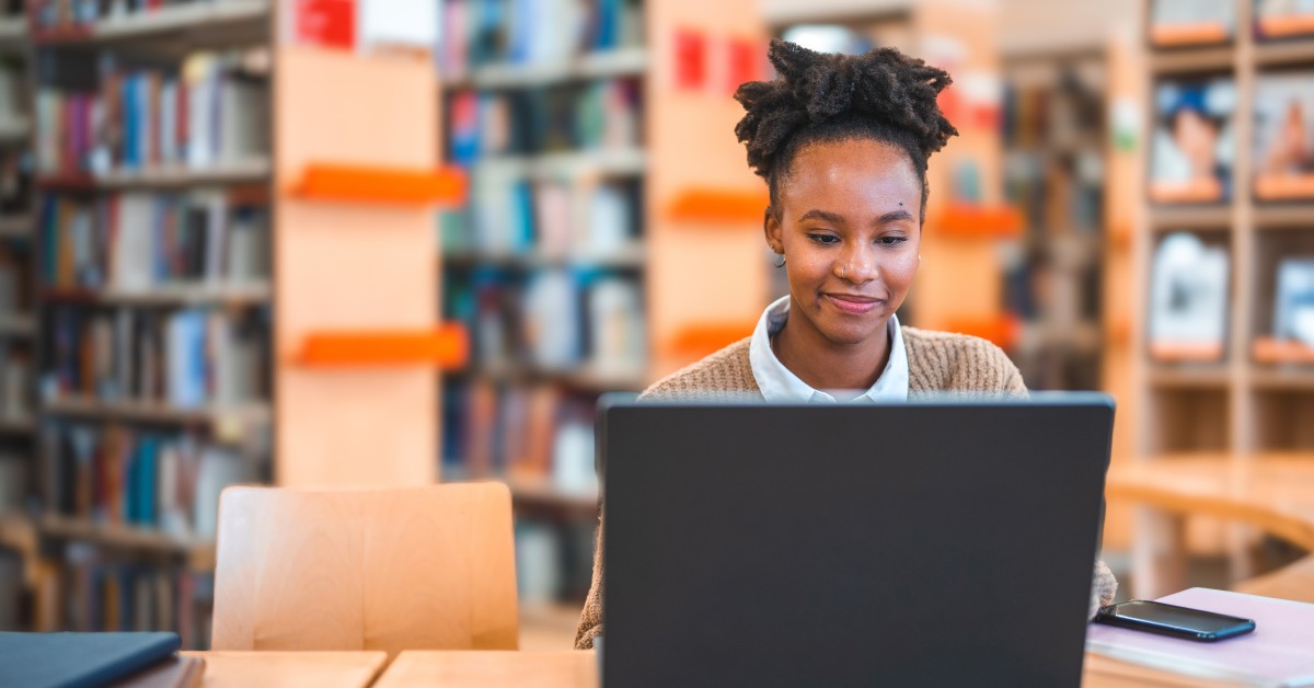 Photo of a person working at a laptop in a library