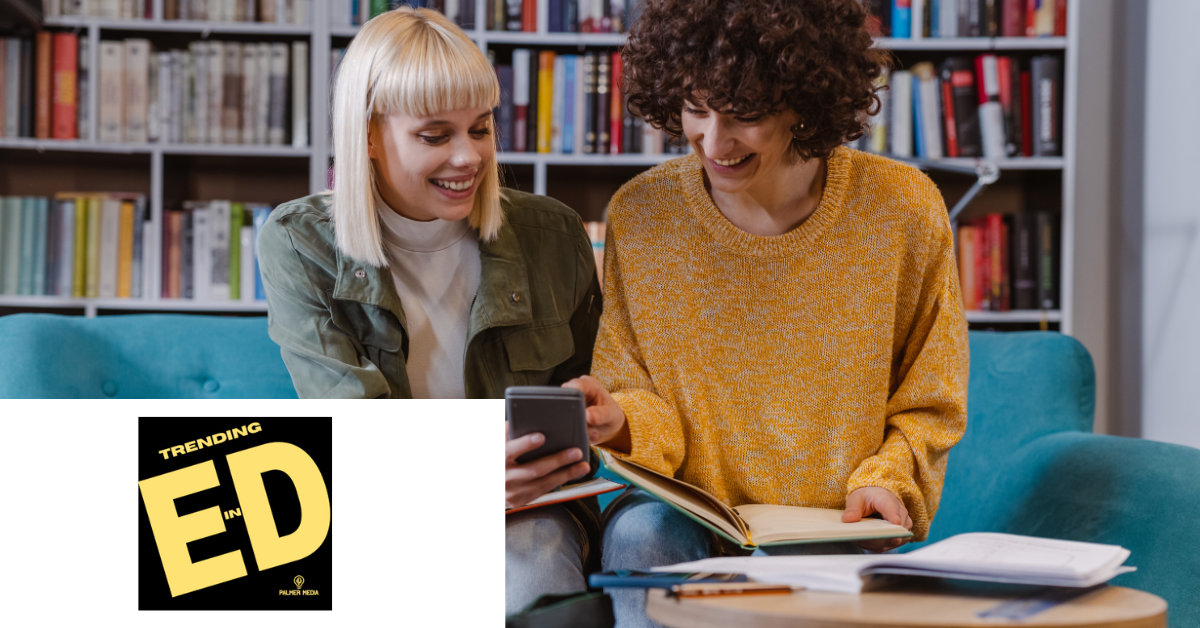 Photo of two people in a library setting looking at something on a phone