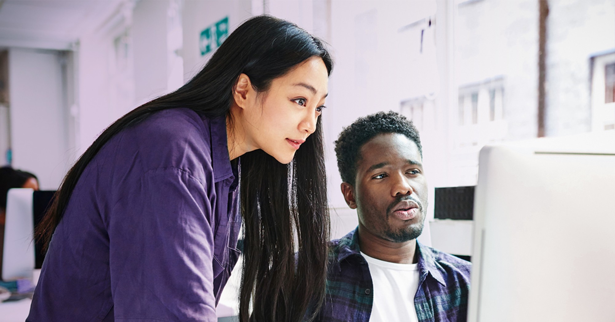 Two coworkers looking at a computer screen