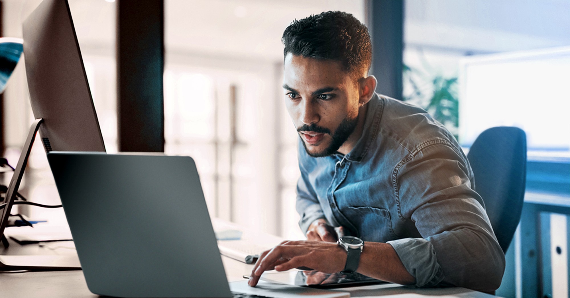 Man working on a laptop at a desk in office setting