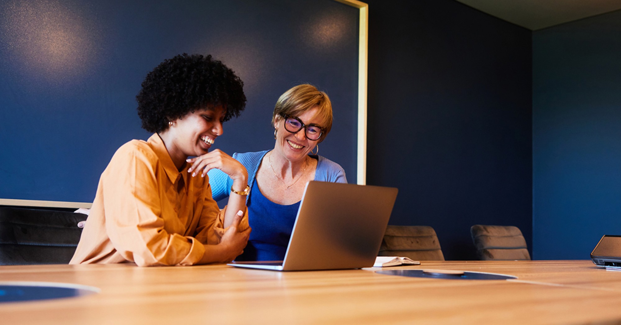 Photo of two people working at a laptop in an office setting