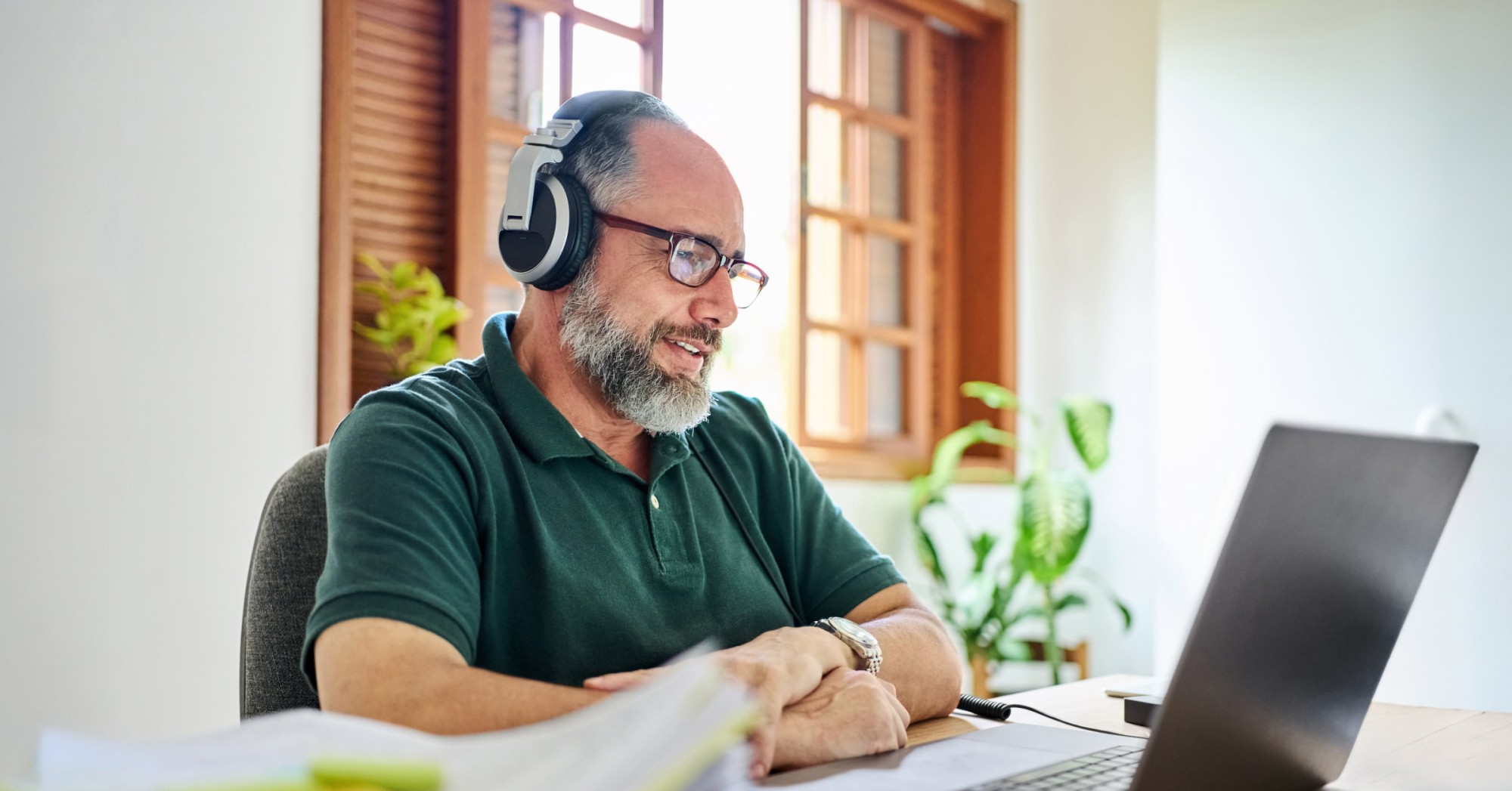 Photo of a person working at a laptop wearing headphones